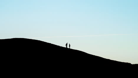 silhouette of men doing topographic surveyings on top of black hill