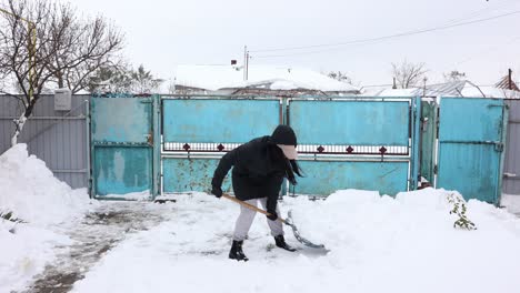 mujer limpiando nieve con pala durante el invierno - amplia