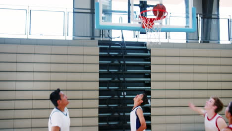 male high school basketball team scoring basket on court and celebrating