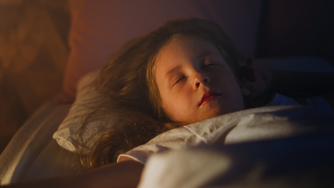 Sweet girl sleeps with eyes blinking under eyelids on bed