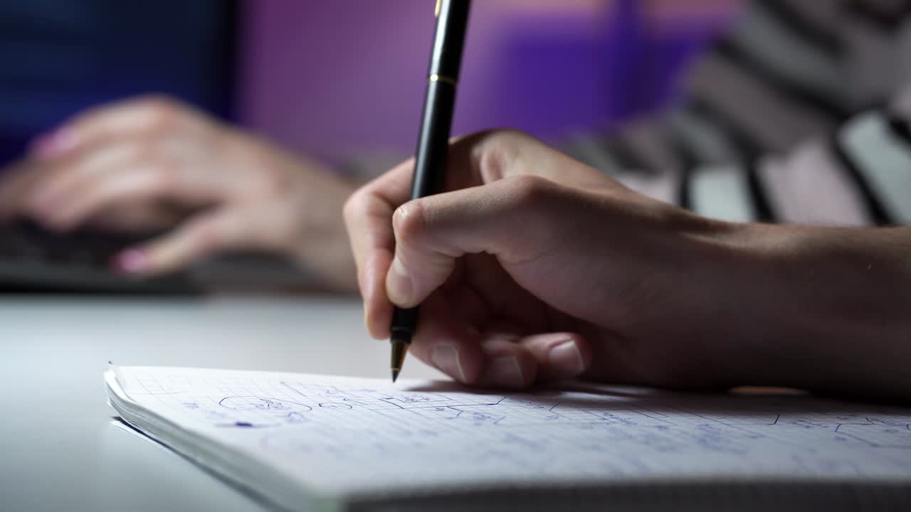 Macro footage of man tracing a schema and a woman typing on keyboard on the background