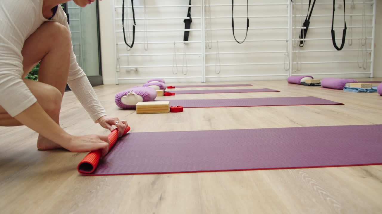 Woman Rolling Up Red Yoga Mat After Class in Studio