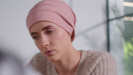 close up of serious young woman patient wearing headscarf undergoing chemotherapy treatment for breast cancer meeting with oncologist or doctor in hospital 4