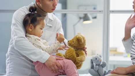 asian pediatrician playing with child and talking with mother