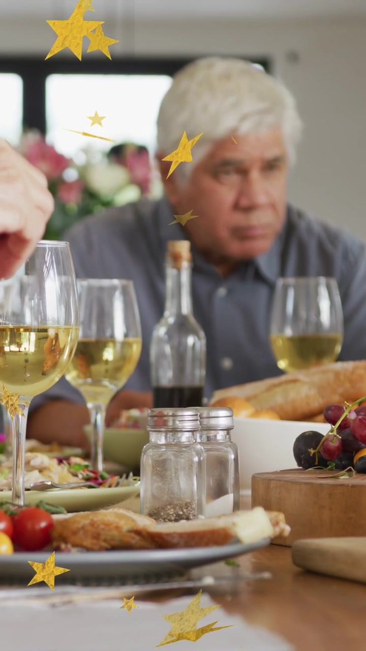Video verticale: La telecamera mette a fuoco, con stelle dorate che fluttuano su un panino, del vino e un anziano che brinda durante un pasto.