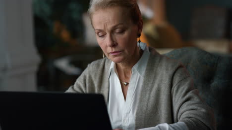 old woman working laptop computer at home