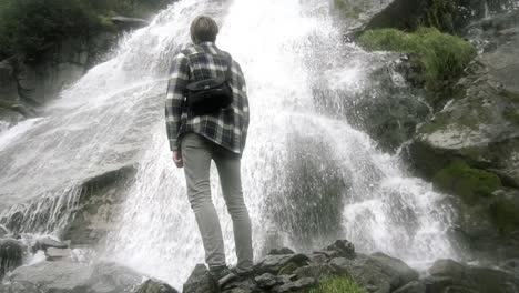 man standing in front of a beautiful waterfall in norway, europe at day time