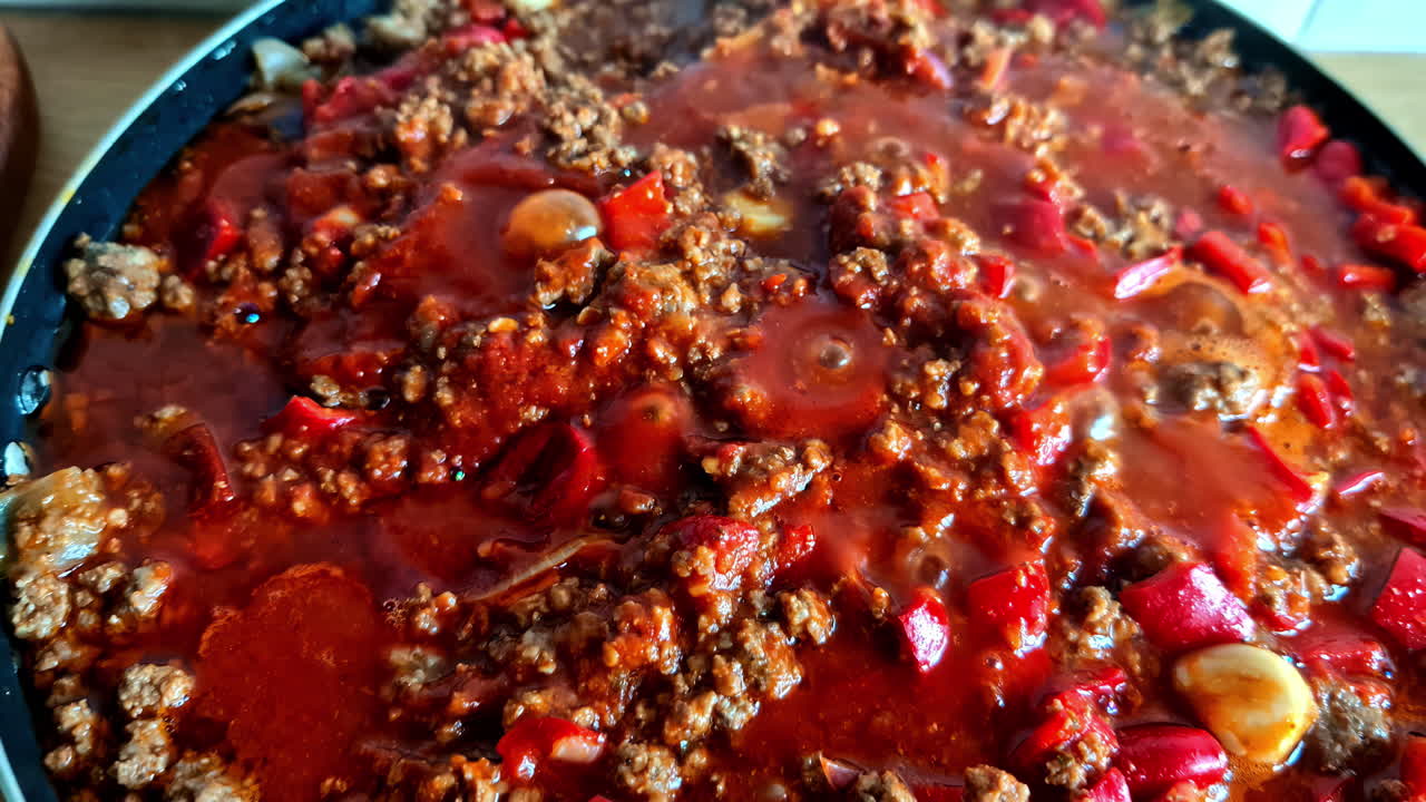 Simmering Bolognese sauce with minced meat, tomatoes, and vegetables in a frying pan