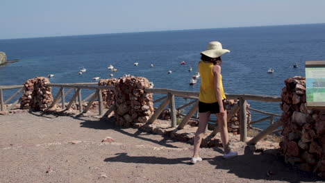 mujer joven caminando hacia el mirador del acantilado, paisaje escénico del océano, españa