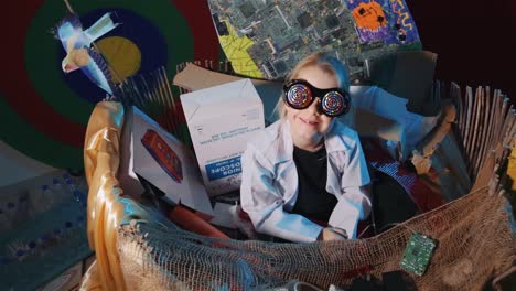 a young girl in a scientist lab gown puts on funny glasses, poses and smile at the camera. - high angle shot