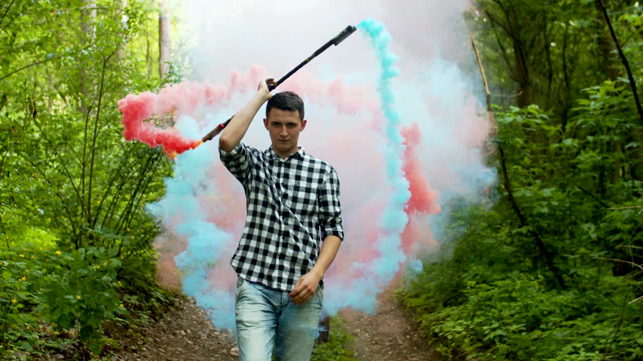 hombre creando un círculo de humo de colores entre el bosque