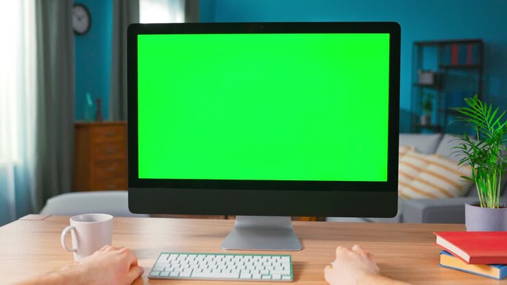 Primo piano di una mano maschile che usa il mouse del computer. Moderno computer personale con display mock-up a schermo verde posizionato sulla scrivania di una casa accogliente. Vista POV dello schermo vuoto del computer.