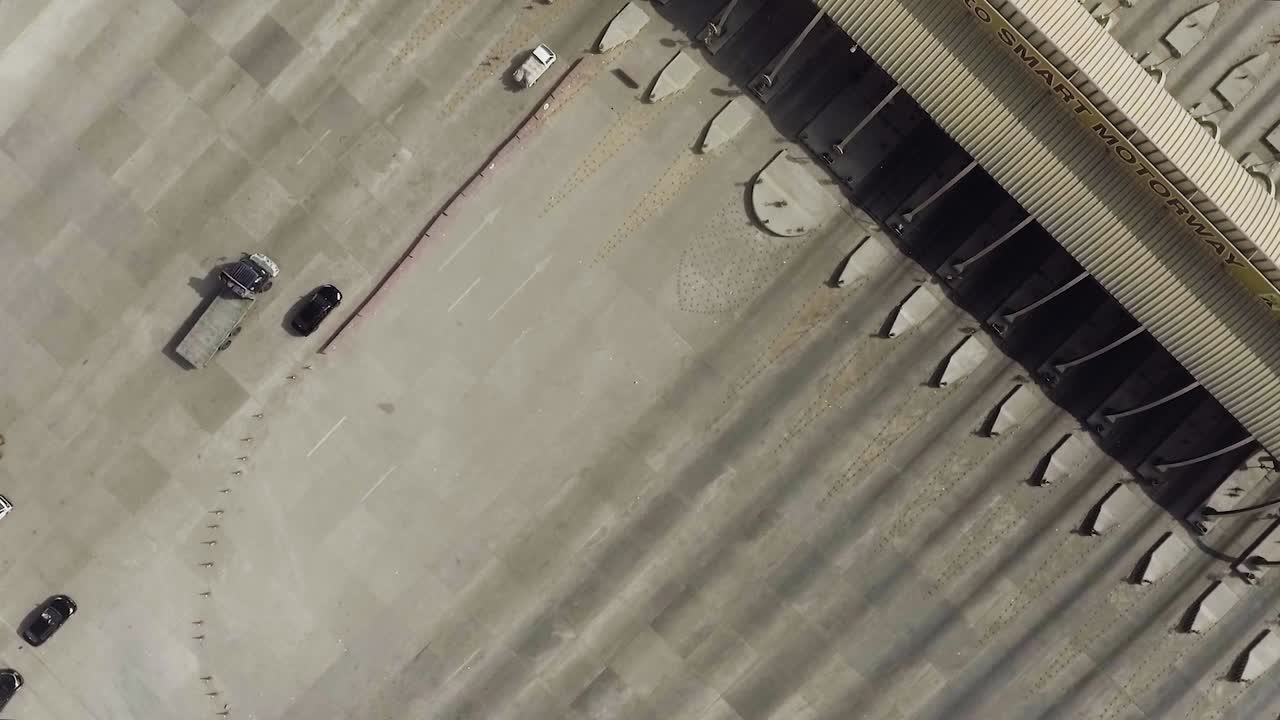 una vista rotacional aérea de una plaza de peaje de la autopista de la ciudad, vehículos pesados y otros que ingresan y cruzan