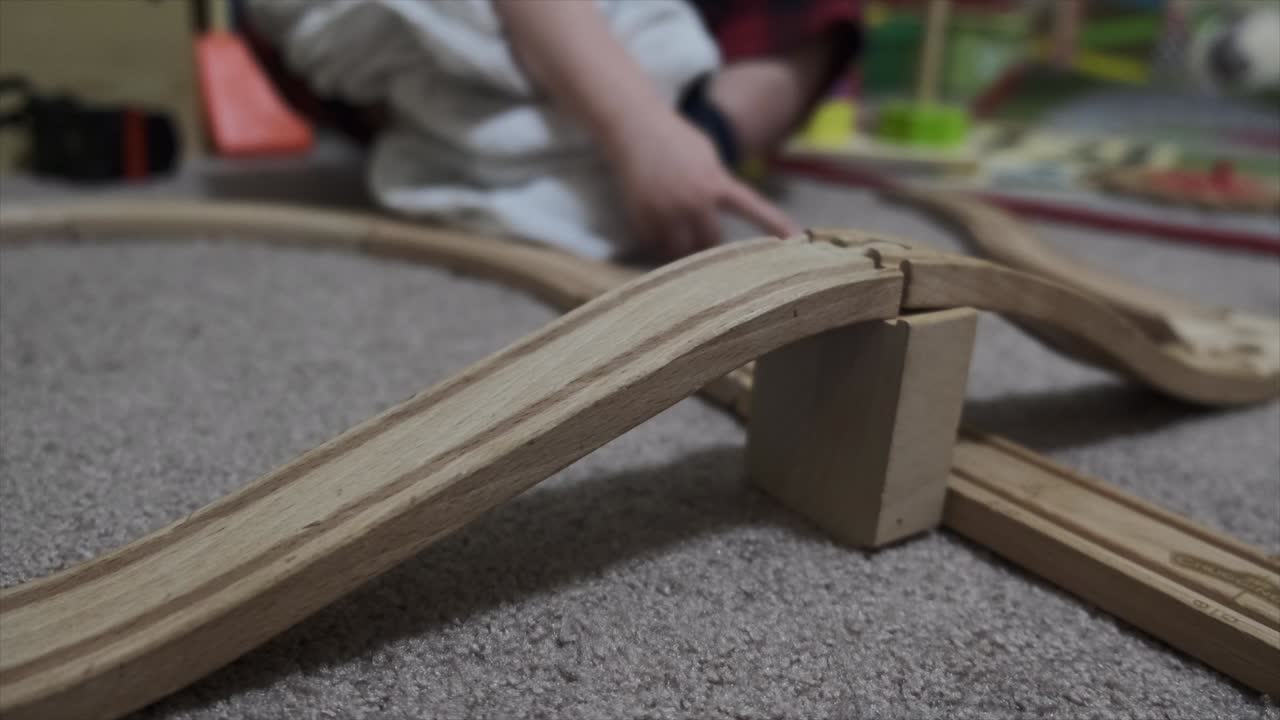 un niño pequeño y un padre jugando juntos con un tren de madera