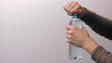 young man unscrewing a plastic bottle and closing it