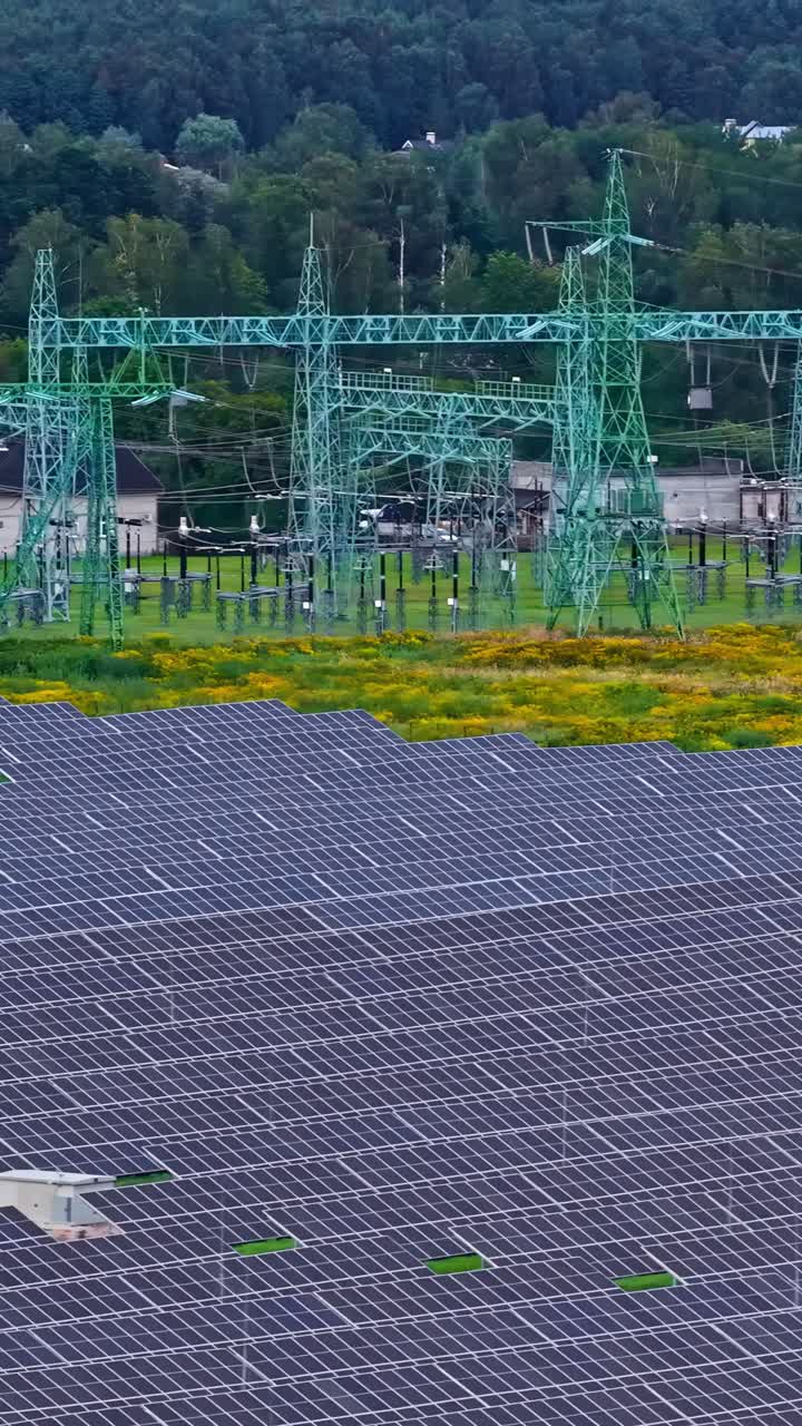 Vertical aerial tracking across solar infrastructure over farmland, straight panel lines and energy grid