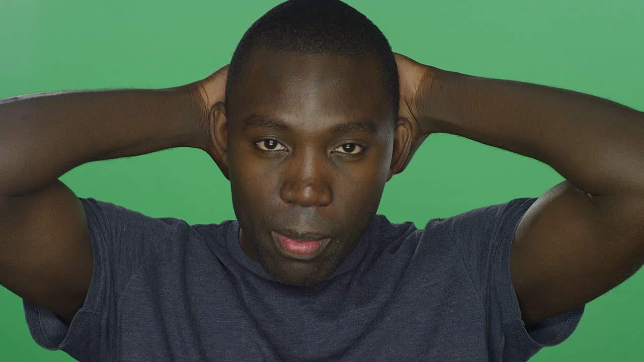 Young African American man looks sad and upset, on a green screen studio background