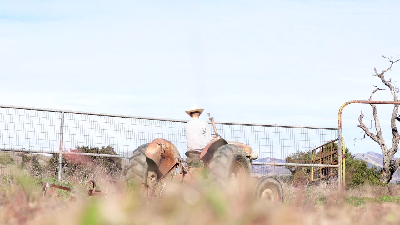 un vaquero conduciendo un tractor y un pequeño bolígrafo redondo