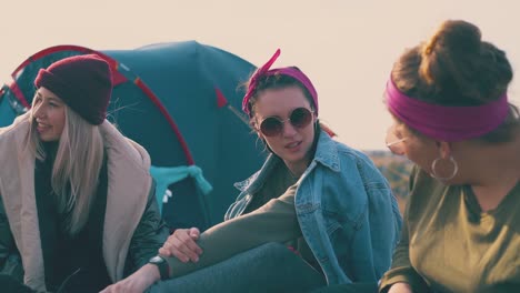 positive women hikers rest talking at tent in warm evening