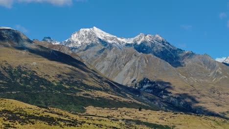 clouds cast dark shadow over mountainous landscape of glenorchy with snow covered peak