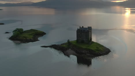 an aerial view of castle stalker on loch laich as the sun begins to set