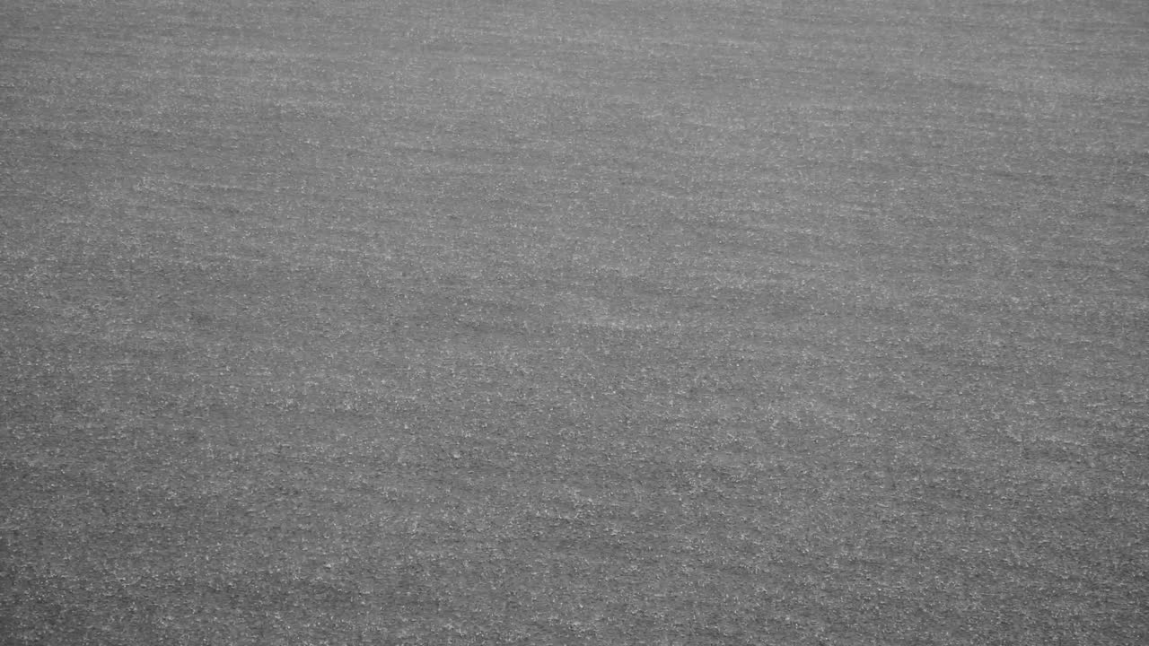 Splashes of water out of big raindrops falling on the alpine lake during the windy and rainy day