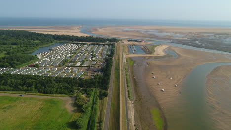 Un-Dron-Aéreo-Alto-Derribó-La-Línea-De-Bancos-De-Pozos-Junto-Al-Mar-Durante-La-Marea-Baja-Con-Veleros-Y-Un-Parque-De-Casas-Estáticas-Para-Caravanas