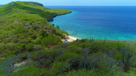 Dense-shrub-land-and-cactus-hillside-overlooks-San-juan-beach,-curacao