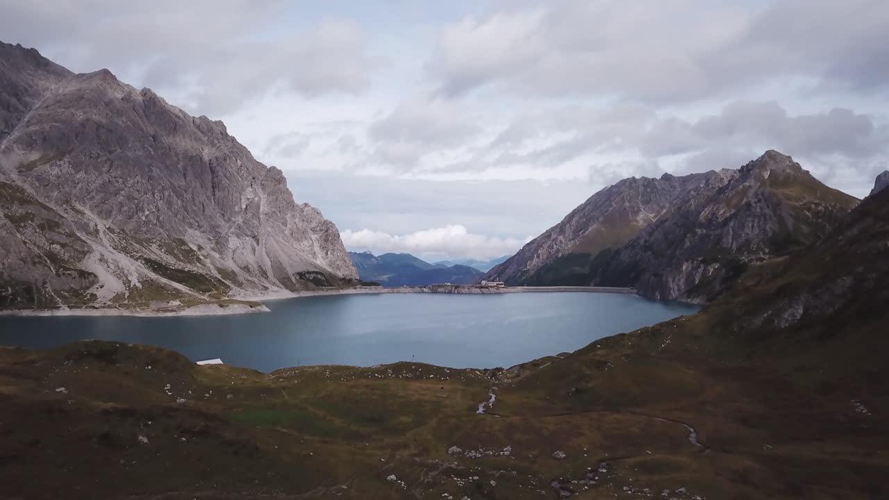 três pessoas estão caminhando nos alpes - voo de drone sobre algumas pessoas nos alpes perto do lago