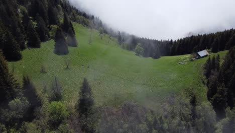 Toma-De-Drones-Del-Claro-De-La-Montaña-Con-Una-Pequeña-Casa-Sobre-Las-Nubes