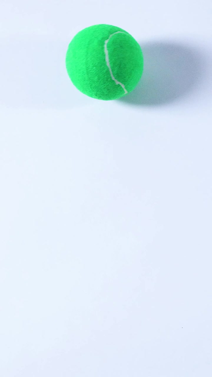 A tennis ball rolls across a smooth surface