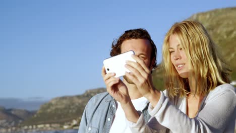 couple taking selfie on mobile phone at beach