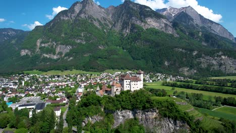 Weißes-Schloss-In-Europäischen-Bergen-Mit-Stadt-Darunter---Antenne-Nach-Rechts-Drehend