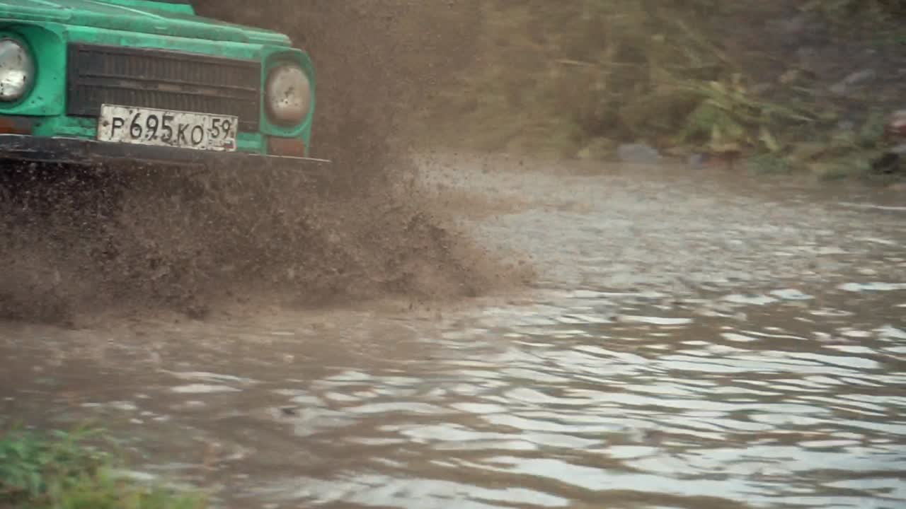 un jeep verde conduciendo a través del barro
