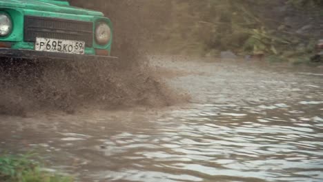 green jeep driving through mud