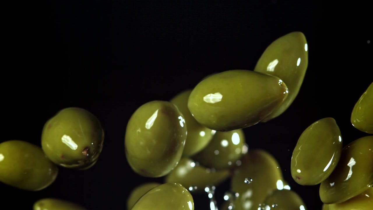 Olive verdi fresche che cadono e schizzano al rallentatore