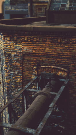 primer plano de una tubería oxidada y una pared de ladrillo en un edificio industrial