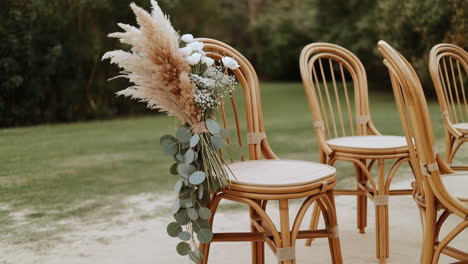 rattan chairs decorated with pampas grass and eucalyptus for an outdoor event