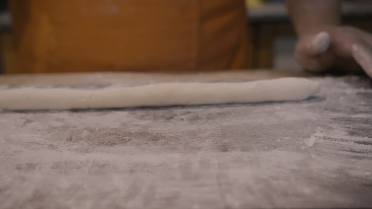 Mani che stendono l'impasto su una superficie infarinata per la cottura