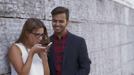 multiethnic couple using cell phone on street