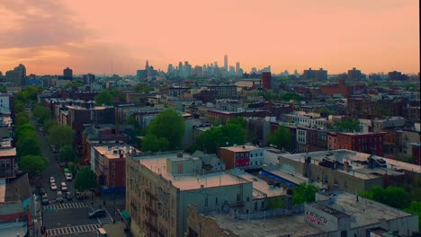 rising nyc golden hour sunset aerial view over brooklyn rooftops revealing manhattan skyline 4k