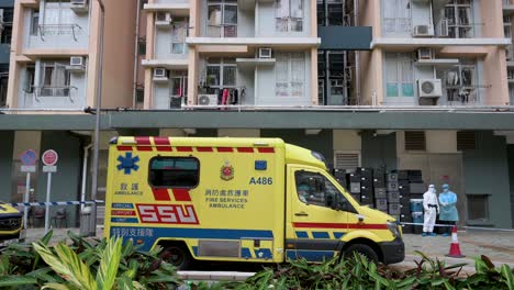 an ambulance and health workers prepare for a mass number of covid-19 coronavirus positive cases outside a public housing building complex placed under lockdown