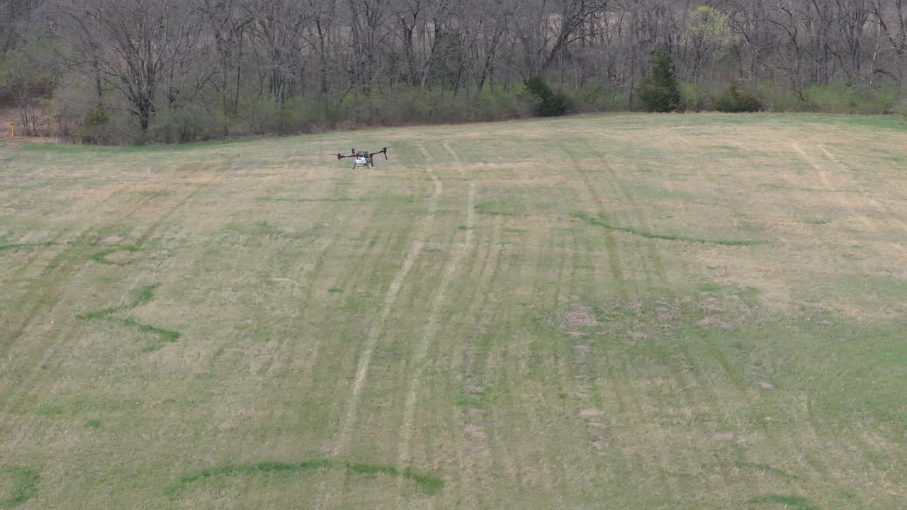 Ag spraying drone flies over a field, spreading chemicals over grasslands