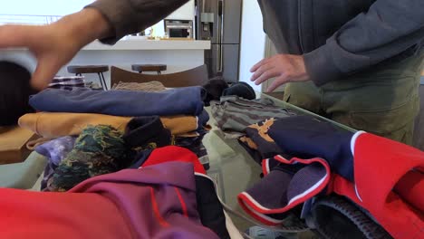 a man separates his socks from folded washing on a dining room table