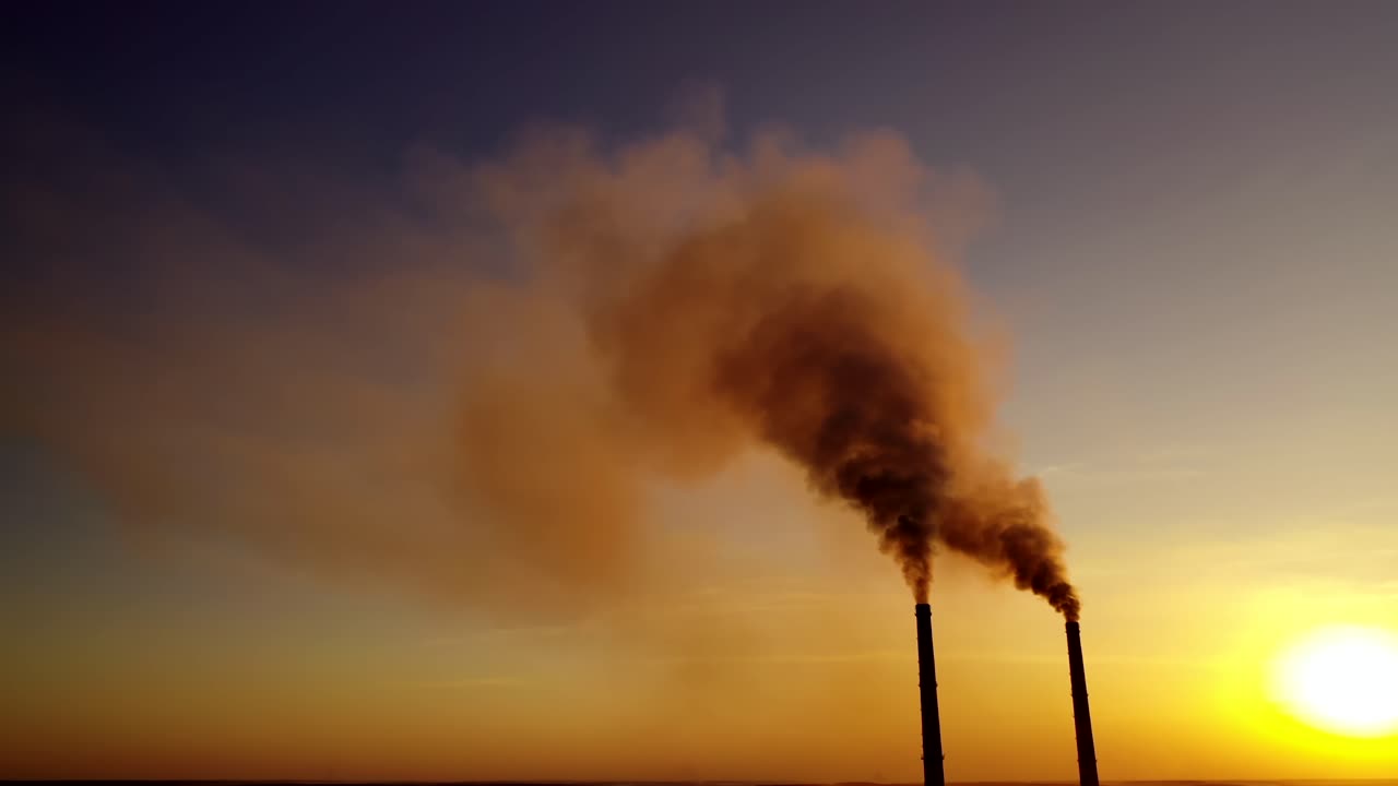 Aerial view of smoke from chimneys. Factory pipe polluting air against sunset