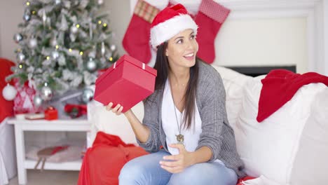 una joven curiosa sacudiendo un regalo de navidad