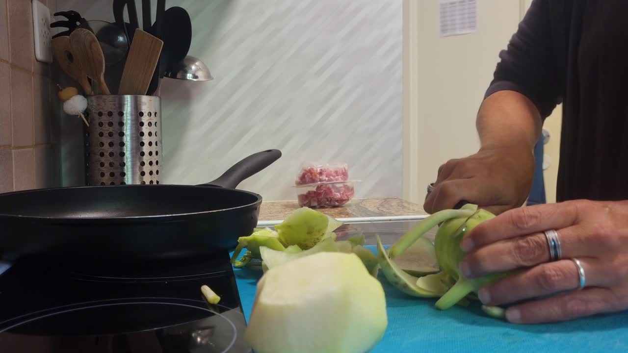 Close-up of woman cutting two kohlrabi (cabbage turnips) in her kitchen, preparing a wholesome vegetarian dish. Daily life, healthy home cooking and fresh produce in focus, Switzerland, Europe