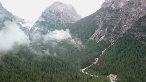 fast tilt up reveal drone shot of the alps with low clouds over a river