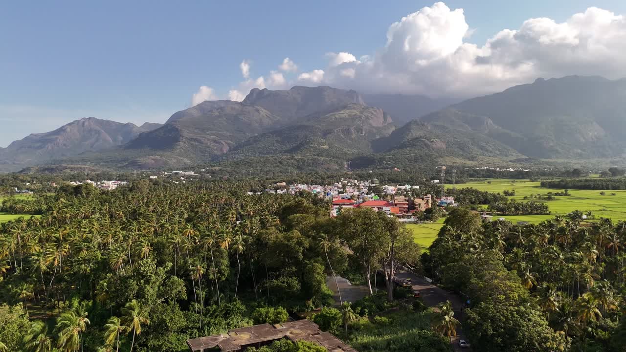A wide, cinematic aerial shot of Courtallam framed by the towering Western Ghats and lush greenery, highlighting its signature waterfall. Great for travel documentaries and wellness promos