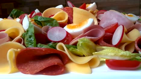 colorful family food platter made of vegetables, soft boiled eggs, salami, and cheese, slide right